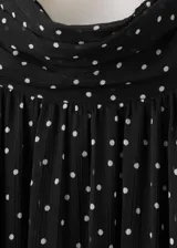 Vestido midi de gasa negro con estampado de lunares blancos, cuello alto, manga larga con volados en los puños y falda con vuelo.