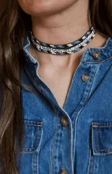 Gargantilla tipo choker de doble vuelta, compuesta por una tira de cuentas pequeñas en tonos azul, negro y blanco, y una tira central de strass brillante.