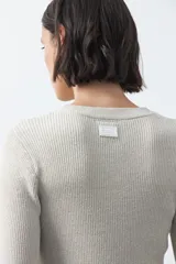 Top de tejido acanalado con sutil acabado metalizado, de silueta entallada con diseño peplum en la cintura y mangas largas levemente acampanadas.