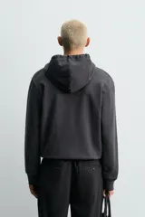 Sudadera de corte relajado confeccionada en tejido compacto de algodón con interior forrado, cuello con capucha, manga larga, bolsillos frontales tipo canguro y acabados en rib.