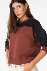 Buzo de cuello redondo con diseño de bloques de color en gris y negro, mangas largas y detalle bordado en el pecho.