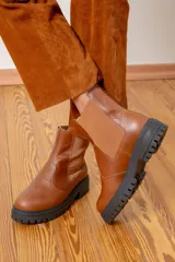 Bota tipo chelsea de cuero color chocolate con acabado brillante, paneles laterales elásticos y suela track negra de goma.