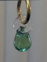 Aros tipo argolla dorada con dije colgante de vidrio soplado en forma de lágrima color verde.