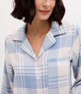 Pijama de dos piezas estilo americano confeccionado en franela. La blusa cuenta con cuello solapa, manga larga, cierre frontal con botones y un bolsillo en el pecho. El pantalón posee cintura elástica. Ambas prendas presentan un estampado de cuadros en tonos azul y blanco.