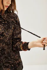 Camisa de modal con estampado abstracto en tonos oscuros y tierra, de corte clásico con cuello camisero, cierre frontal de botones y mangas largas con puños.