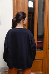 Buzo de felpa color camel con diseño asimétrico cruzado en el frente, cuello redondo y mangas largas con puños elastizados.
