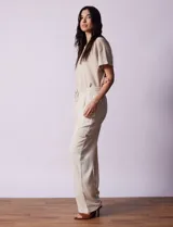 Pantalón cargo de lino a rayas verticales grises y blancas, marca Marissa Olivia. Pretina ancha elastizada con lazo de ajuste, bolsillos inclinados delanteros y bolsillos laterales con botón.