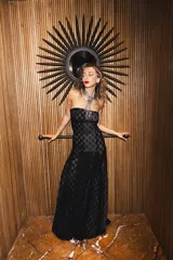 Vestido largo strapless de encaje negro con transparencias y espalda descubierta con tiras cruzadas, de corte entallado y falda de caída suelta.