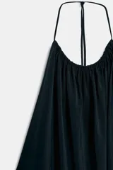 Vestido midi negro con cuello halter, lazada ajustable en el cuello y diseño fluido con espalda descubierta.