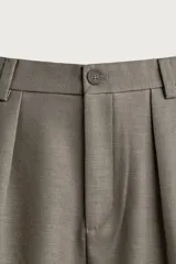 Pantalón relaxed fit de color blanco off-white, confeccionado en tejido con lino. Cuenta con pliegues frontales en la cintura, bolsillos delanteros y cierre frontal con cremallera y botón.