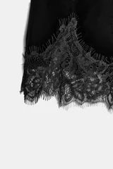 Bermuda de tiro alto confeccionada en terciopelo negro, con cintura elástica y bajo decorado con aplicación de encaje a tono.