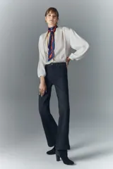 Pantalón de jean negro de tiro medio, corte ajustado en la cintura y muslos, y acampanado desde la rodilla hasta el ruedo. Confeccionado en tejido confort con elastano, cierre y botón.