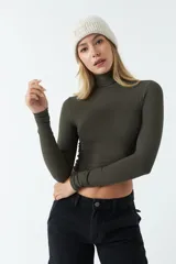 Polera de manga larga ajustada al cuerpo, confeccionada en tejido rib de algodón. Presenta cuello alto y diseño corto tipo crop top.