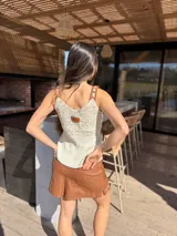 Top de diseño combinado con tejido de crochet en la parte superior y cuero en la inferior, con escote en V y tirantes finos.