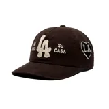 Gorro tipo dad hat color negro con bordado frontal en color crudo con las letras 'LA' en el centro y las frases 'Mi CASA' y 'Su CASA' a los lados.