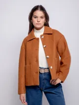 Tapado corto de paño color tostado, con cuello camisero, cierre frontal de botones veteados y dos bolsillos frontales de parche.