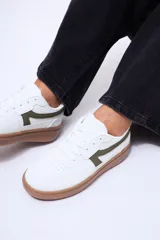 Championes urbanos de diseño minimalista, color blanco con detalles en verde oliva en los laterales y suela de goma color caramelo.