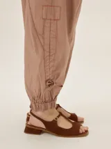 Pantalón de lyocell color tostado, con silueta relajada, bolsillos laterales y detalles de costuras pespunteadas. Cuenta con puños ajustables en los tobillos mediante cordones y elástico.