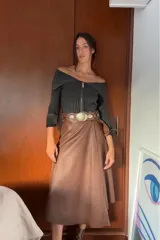 Falda midi color marrón chocolate, de cuero sintético, con corte evasé, cintura alta y cinturón con hebilla circular.