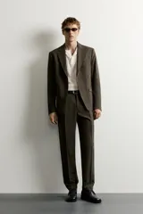 Blazer slim fit de corte sastrero en color verde oscuro, con cuello de solapa de muesca, bolsillos con solapa en la cadera y cierre frontal de botones.