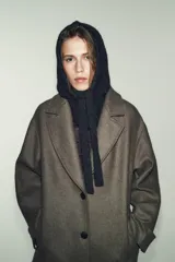 Capucha de punto canalé en color beige, con diseño envolvente y cierre frontal ajustable mediante lazada a tono.