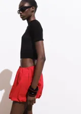 Short de gabardina color rojo con diseño abuchonado estilo globo, cintura elástica y bolsillos laterales.