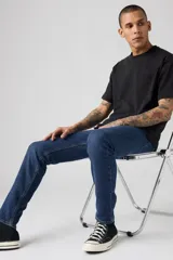 Jeans de mezclilla azul oscuro, corte skinny, con cierre de botones y tiro medio.