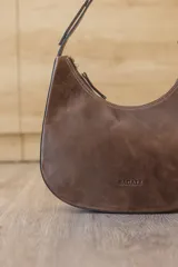 Cartera hobo de cuero color rojo con silueta curva de media luna, cierre superior y correa de hombro ajustable.