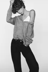 Jeans de tiro alto color negro con efecto lavado, corte mom fit, cinco bolsillos y cierre frontal con cremallera y botón metálico.