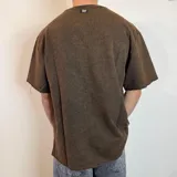 Remera de corte oversize en color verde oliva con efecto lavado, confeccionada en tela rústica pesada, con cuello redondo y bordes sin costura.