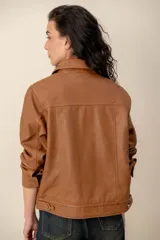 Campera de cuero marrón, con cuello camisero, cierre frontal con botones metálicos y bolsillos frontales.