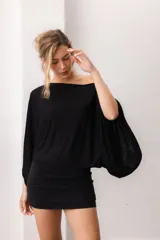 Blusa fluida de color marrón, con diseño holgado, escote bote que deja un hombro al descubierto y mangas anchas y cortas.