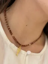 Collar de cuentas de piedra del sol marrón con destellos, con dije colgante en forma de pez con baño dorado.