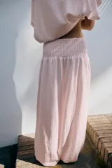 Pantalón baggy de tiro medio color rosado, con cintura elástica fruncida tipo nido de abeja y bajos ajustables con cordones.