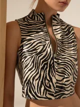 Top corto de cuero ovino con estampado de cebra, cuello alto y cierre metálico frontal.