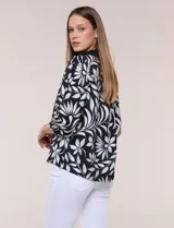 Blusa de calce suelto y caída ligera en color negro con estampado floral blanco, cuello camisero con escote en V y pechera en contraste. Presenta mangas tres cuartos abullonadas con puños elásticos.