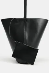 Maxi bolso de hombro de piel en color negro con interior azul y tiras colgantes en el lateral.
