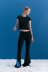 Legging estilo oxford confeccionada en lycra tipo neoprene, con tajo lateral en la botamanga que revela un interior en color azul. Presenta un isologo bordado en el delantero y un calce ajustado que se ensancha hacia el ruedo.