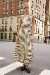 Vestido midi de cuello halter anudado, escote en pico y espalda descubierta, con diseño a rayas verticales y bajo abullonado con elástico interior.