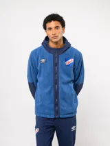 Campera de polar azul con capucha, cierre frontal completo y detalles en tela técnica a tono. Presenta el logo de Umbro y el escudo del Club Nacional de Football bordados en el pecho.