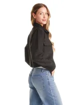 Chaqueta de estilo camisero confeccionada en tejido tipo suede, con cuello clásico, cierre frontal mediante botones a presión y bolsillos aplicados en el pecho. Presenta mangas largas con puños ajustables.