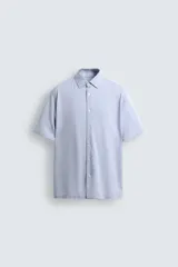 Camisa de manga corta color verde grisáceo, de corte regular fit, confeccionada en tejido suave y elástico con cierre de botonadura frontal.