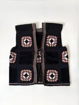 Chaleco negro hecho a mano en Uruguay, compuesto por cuadrados de cuero vacuno y cuadrados de crochet con hilo 100% algodón. Presenta un diseño de cuadrados de crochet en tonos beige, marrón y blanco, y un cierre frontal con cordones.