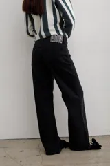 Pantalón de jean negro de corte recto y tiro medio, con cierre frontal de botón y cremallera, y bolsillos laterales y traseros.