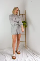 Conjunto de dos piezas en color crema, compuesto por un buzo de cuello alto, mangas largas abullonadas y ajuste en la cintura, junto con un short de tiro alto con terminaciones al corte.