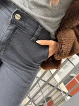 Pantalon de denim negro de corte recto y tiro alto, con aberturas laterales en los tobillos que incluyen cierre de botones a presión y ruedo deshilachado.
