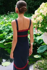 Vestido largo azul marino de Lady Pipa, con tirantes anchos, escote corazón con detalles bordados en rojo y parte inferior translúcida con tajo frontal y ribete rojo.