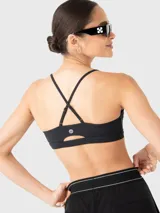 Top deportivo de bajo impacto color negro, con escote redondo y tirantes finos ajustables que se cruzan en la espalda. Cuenta con almohadillas removibles.
