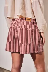Short de tiro alto confeccionado en denim con diseño a rayas en tonos rosados, borravino y blancas. Cuenta con bolsillos delanteros y traseros, presillas para cinto y cierre frontal con botón metálico y cremallera.