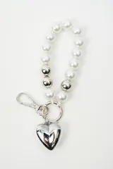 Llavero con tira de cuentas acrílicas estilo perlas blancas intercaladas con esferas plateadas, argolla metálica y dije en forma de corazón plateado.